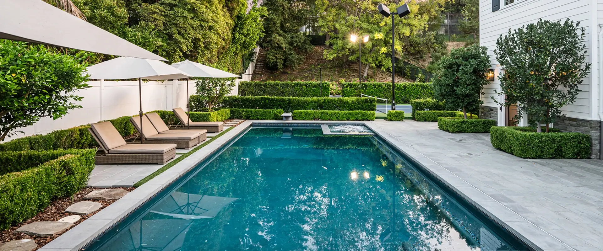 Backyard pool with lounge chairs and umbrellas.